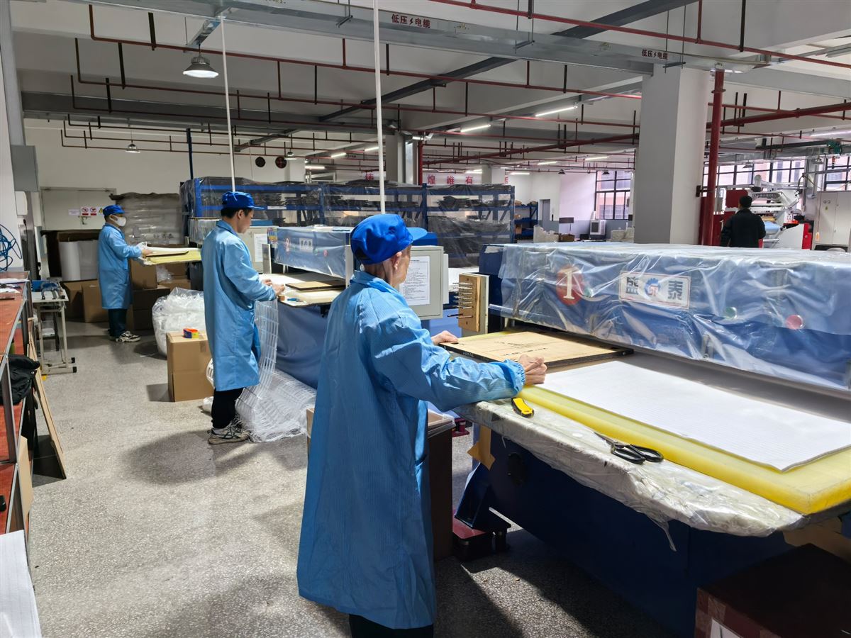 Workers operating filter panel cutting line in the workshop